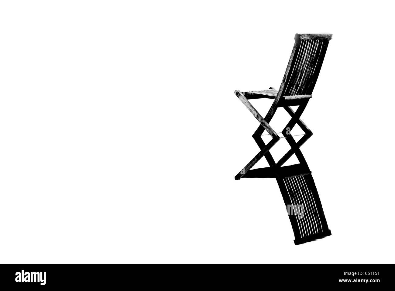 Vieja silla de madera en aguas tranquilas, con reflexión, simbolizando pease, soledad y emptyness Foto de stock