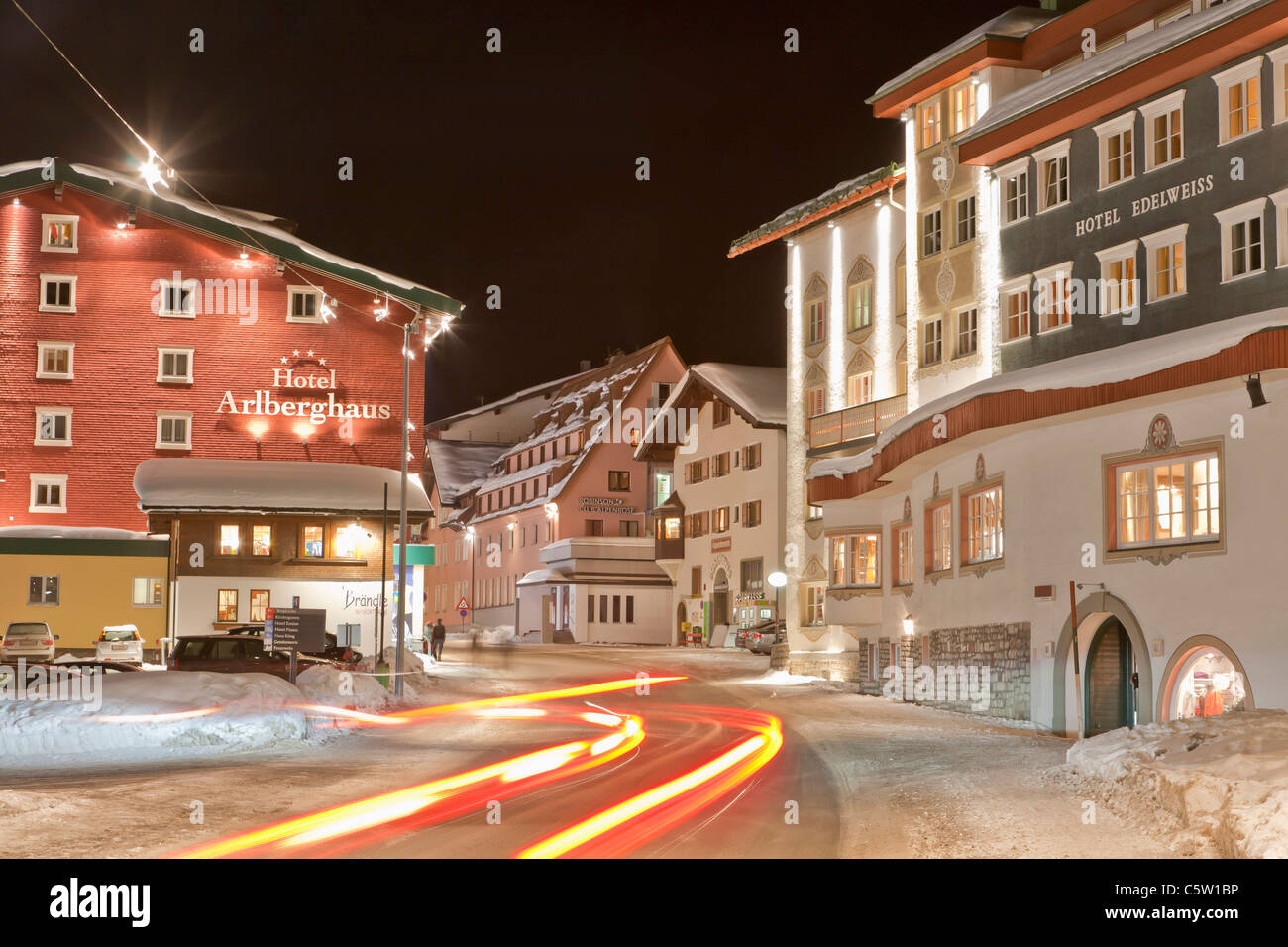 Austria, Vorarlberg, Zurs am Arlberg, Vista de rastro de luz en la carretera principal cerca de hoteles en invierno Foto de stock