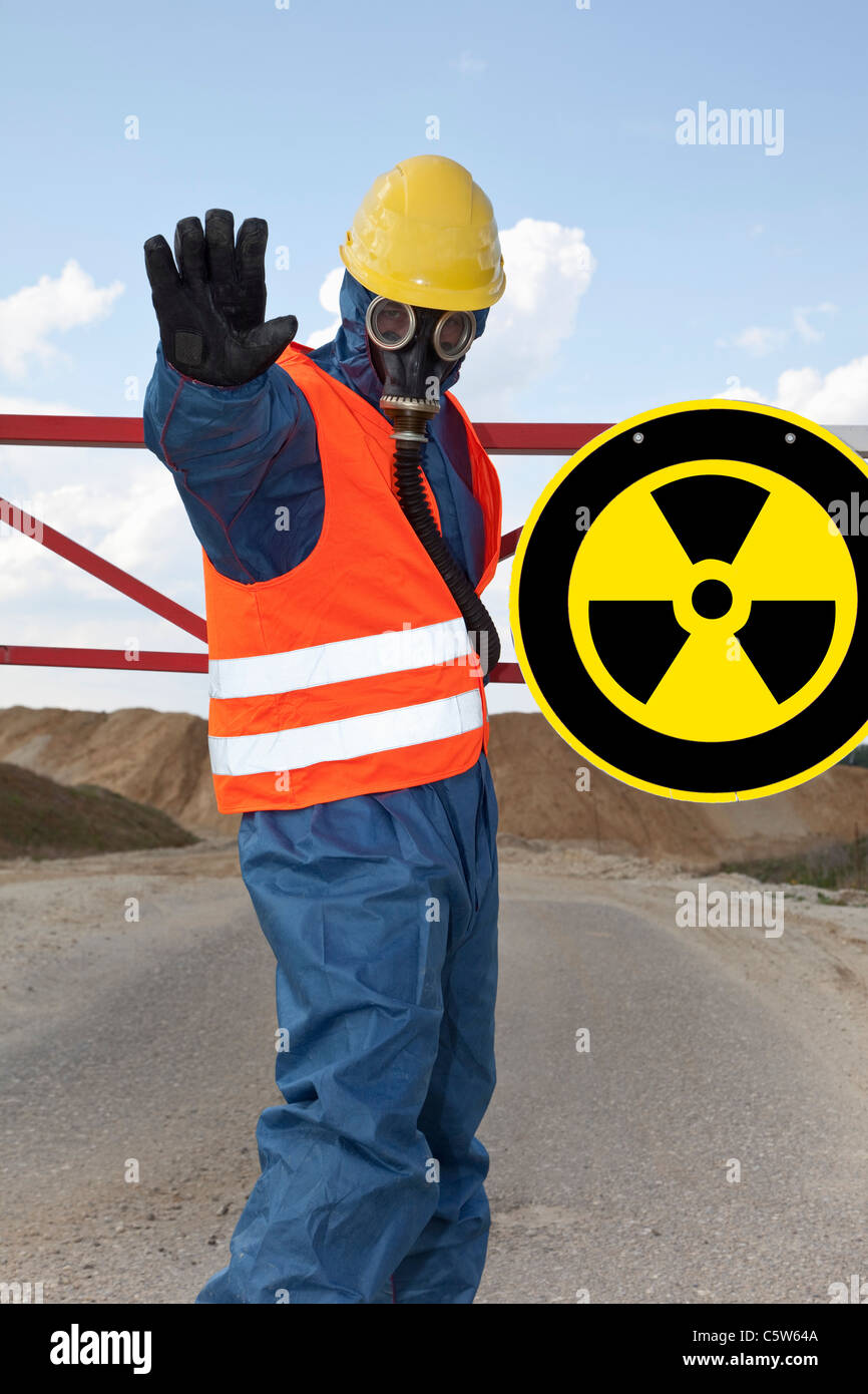 Alemania, hombre en ropa de trabajo protectora radiactivos cerca del símbolo de aviso Foto de stock