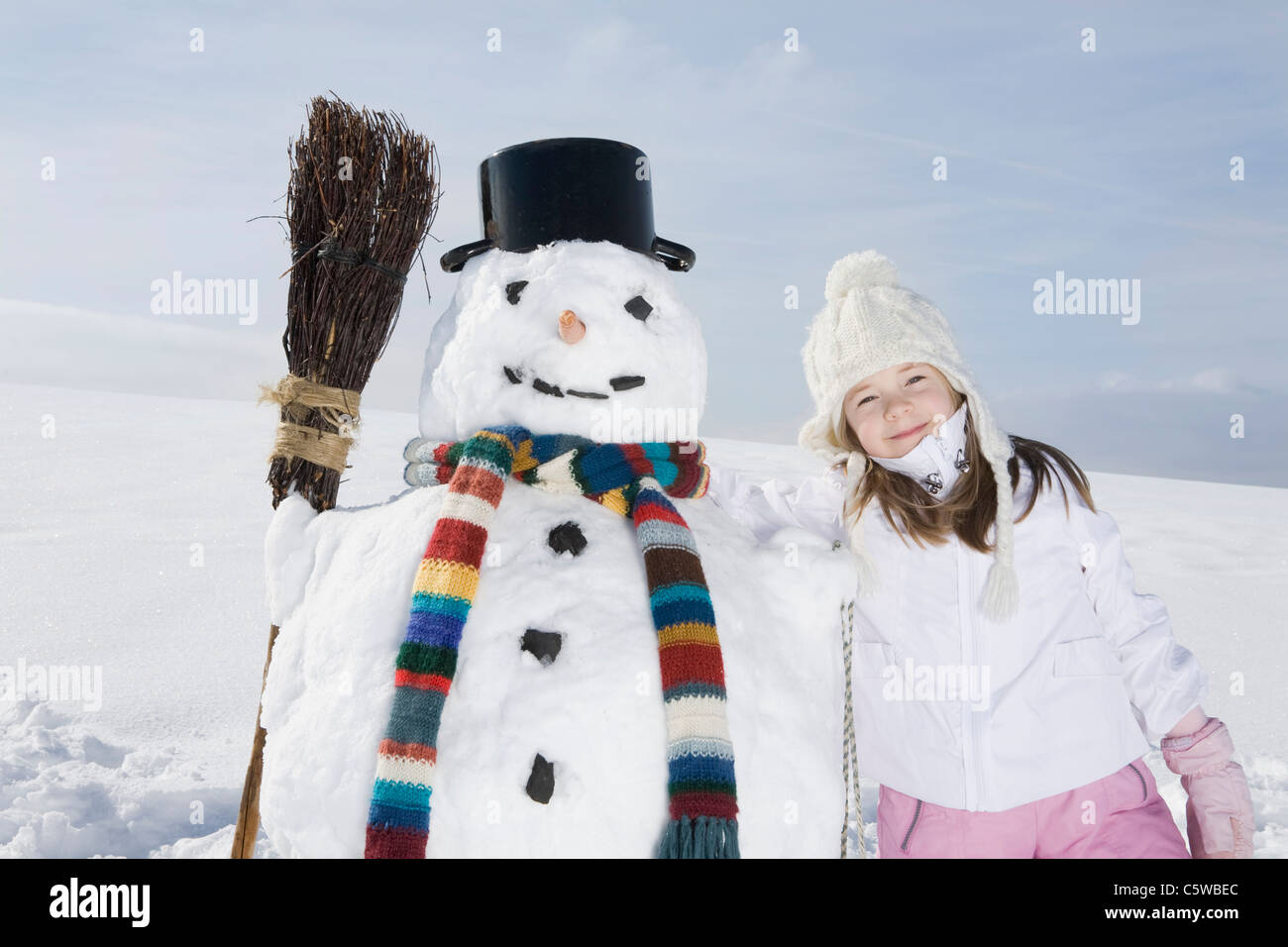 Alemania, Baviera, Munich, Chica (8-9) de pie junto al muñeco de nieve, Retrato Foto de stock
