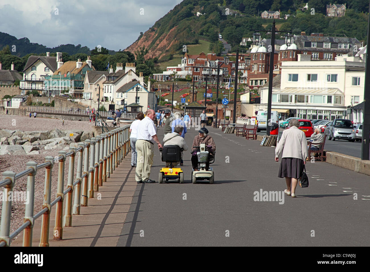Dos scooters de movilidad se reunirán en el paseo marítimo y sus pilotos tienen una conversación en Sidmouth, Devon, Inglaterra, Reino Unido. Foto de stock