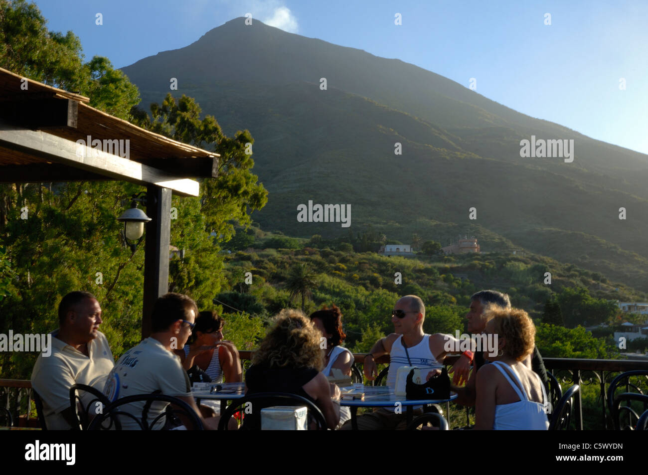 Un grupo de turista sentado en una cafetería en la parte de abajo del volcán de Stromboli Foto de stock