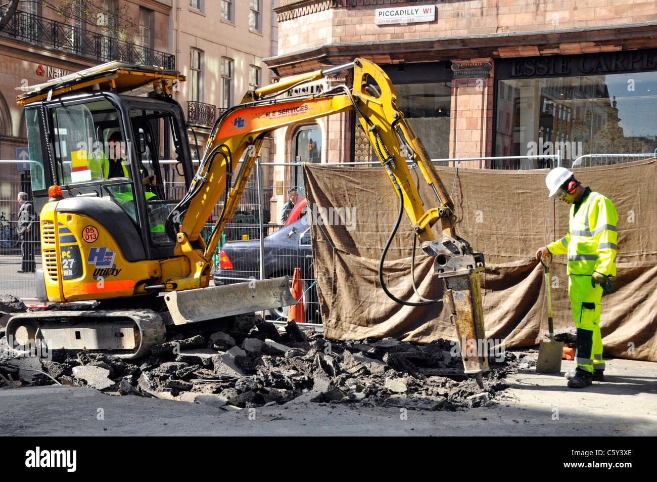 Mini máquina excavadora equipada con martillo neumático ruidosa herramienta  para trabajos de carretera en Piccadilly Londres Inglaterra Fotografía de  stock - Alamy