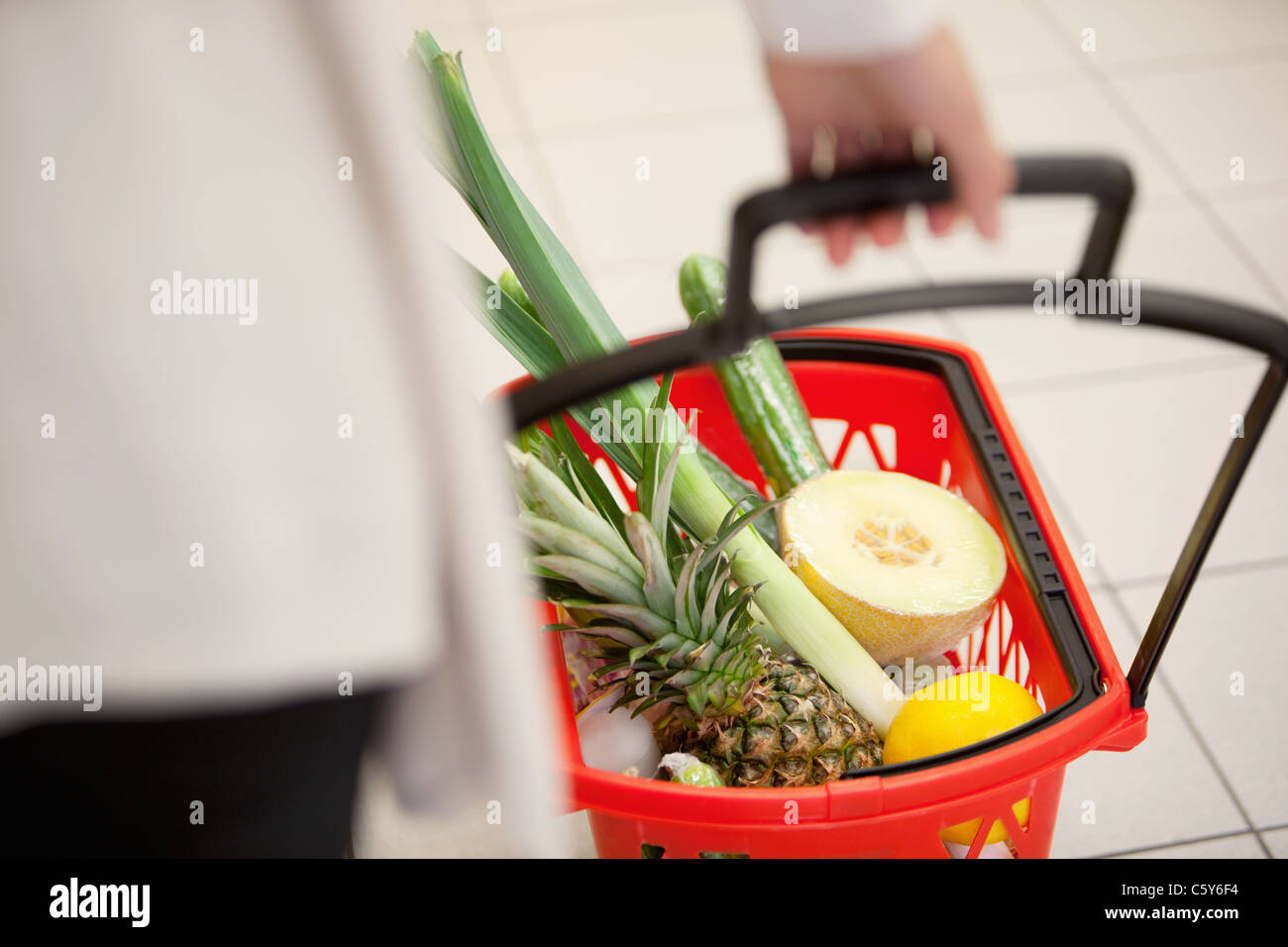 Un alto ángulo de visualización de la mano humana llevando rojo cesta llena de frutas y verduras Foto de stock