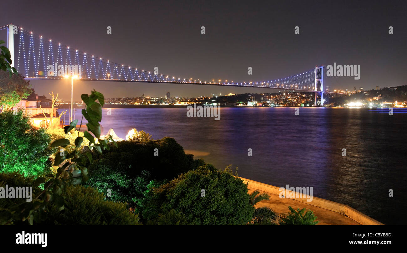 Kpr Bogozici Bosphosrus Río y Puente escena nocturna con reflejos de color lavanda azul del agua y jardines en el foregr Foto de stock