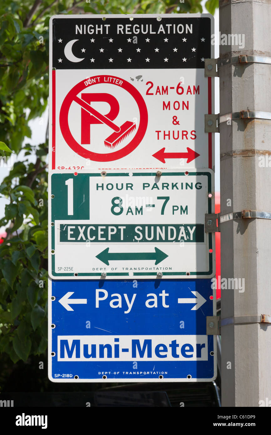 Varias señales indican las diversas regulaciones del estacionamiento en vigor en una calle en la Ciudad de Nueva York. Foto de stock