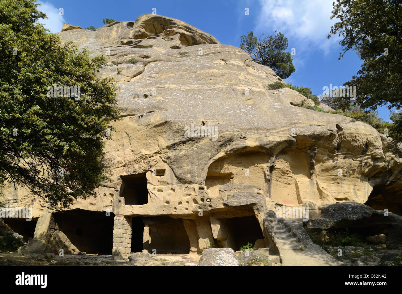 Casas trogloditas, casas cueva, o casas de roca cortada en la cara del acantilado en las Grottes de Calès, Lamanon, Provenza, Francia Foto de stock