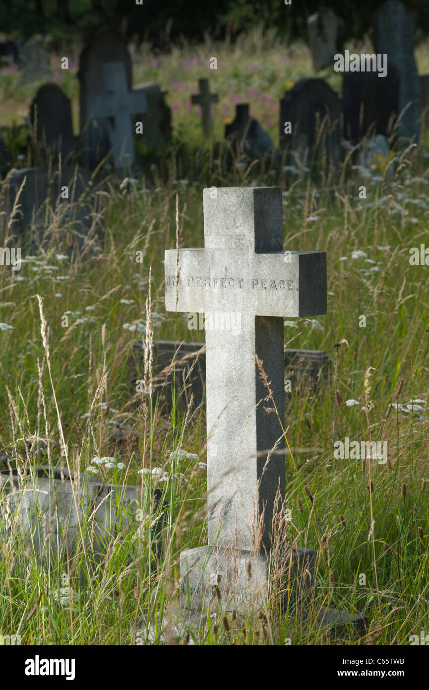 Cruz de piedra para marcar una tumba en un cementerio en el oeste de Londres, Inglaterra, Reino Unido. La inscripción dice: "En perfecta paz" Foto de stock