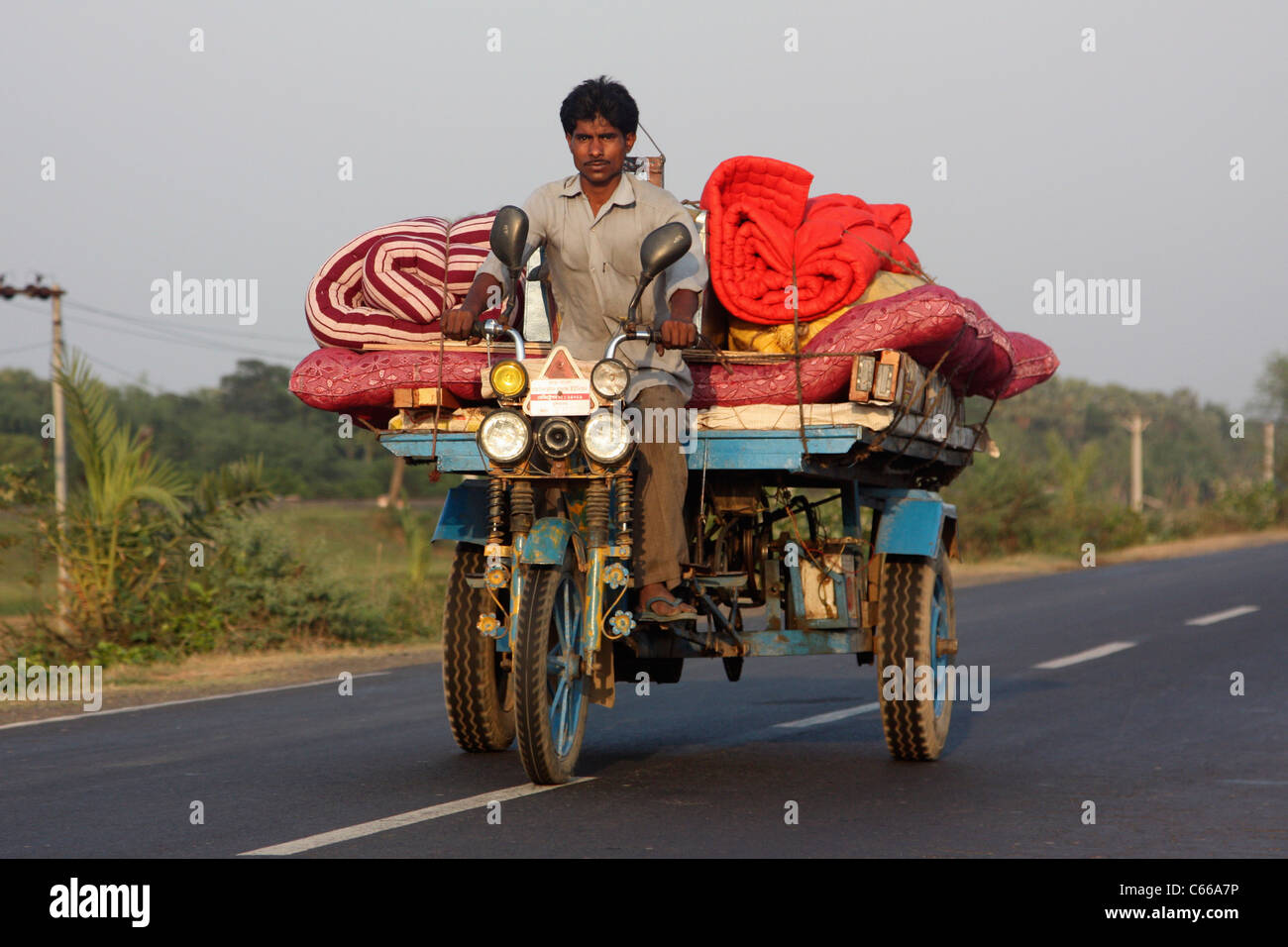 Triciclo de motor indio al atardecer con carga de una autopista en Bengala Occidental, India Foto de stock