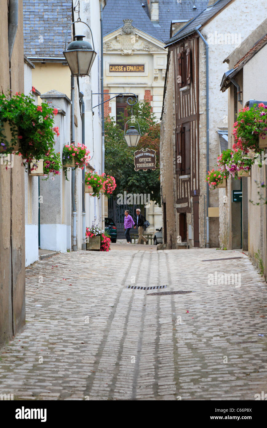 Dos personas en una angosta calle bordeada de flores de adoquines en el centro de la ciudad medieval de Beaugency Valle del Loira Francia Foto de stock