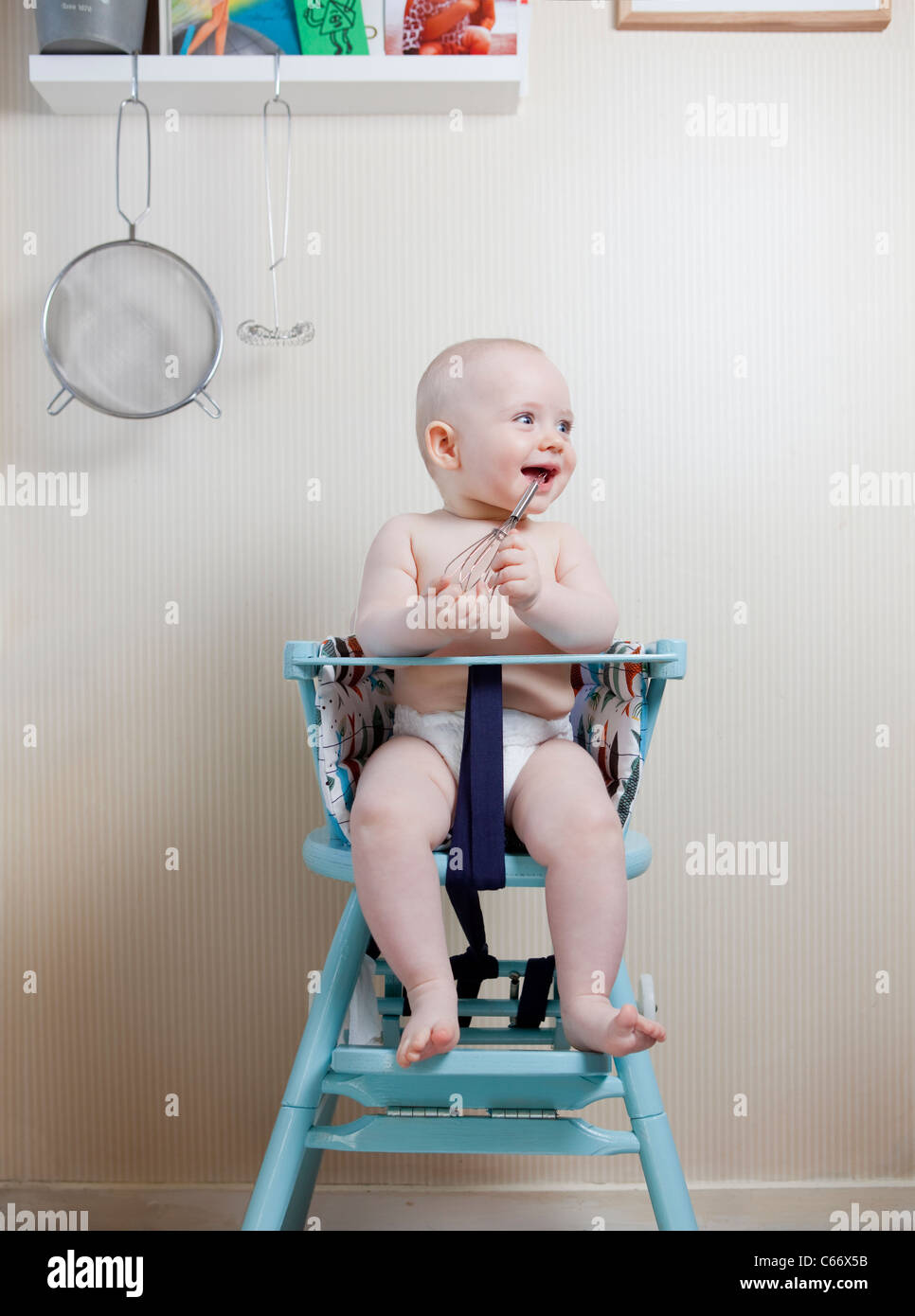 El bebé de 6 meses sentado en la silla de bebé y jugar con utensilios de  cocina Fotografía de stock - Alamy