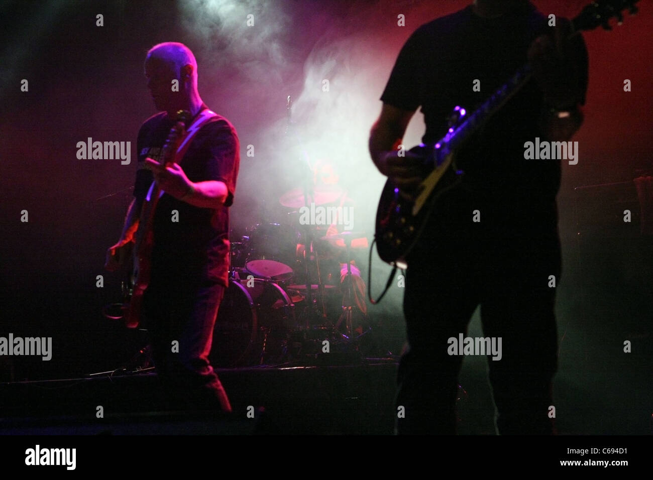 El ritmo y bajo Krimsons guitarristas y un baterista oculto por etapas el humo, durante su actuación en el HMV Forum London Foto de stock