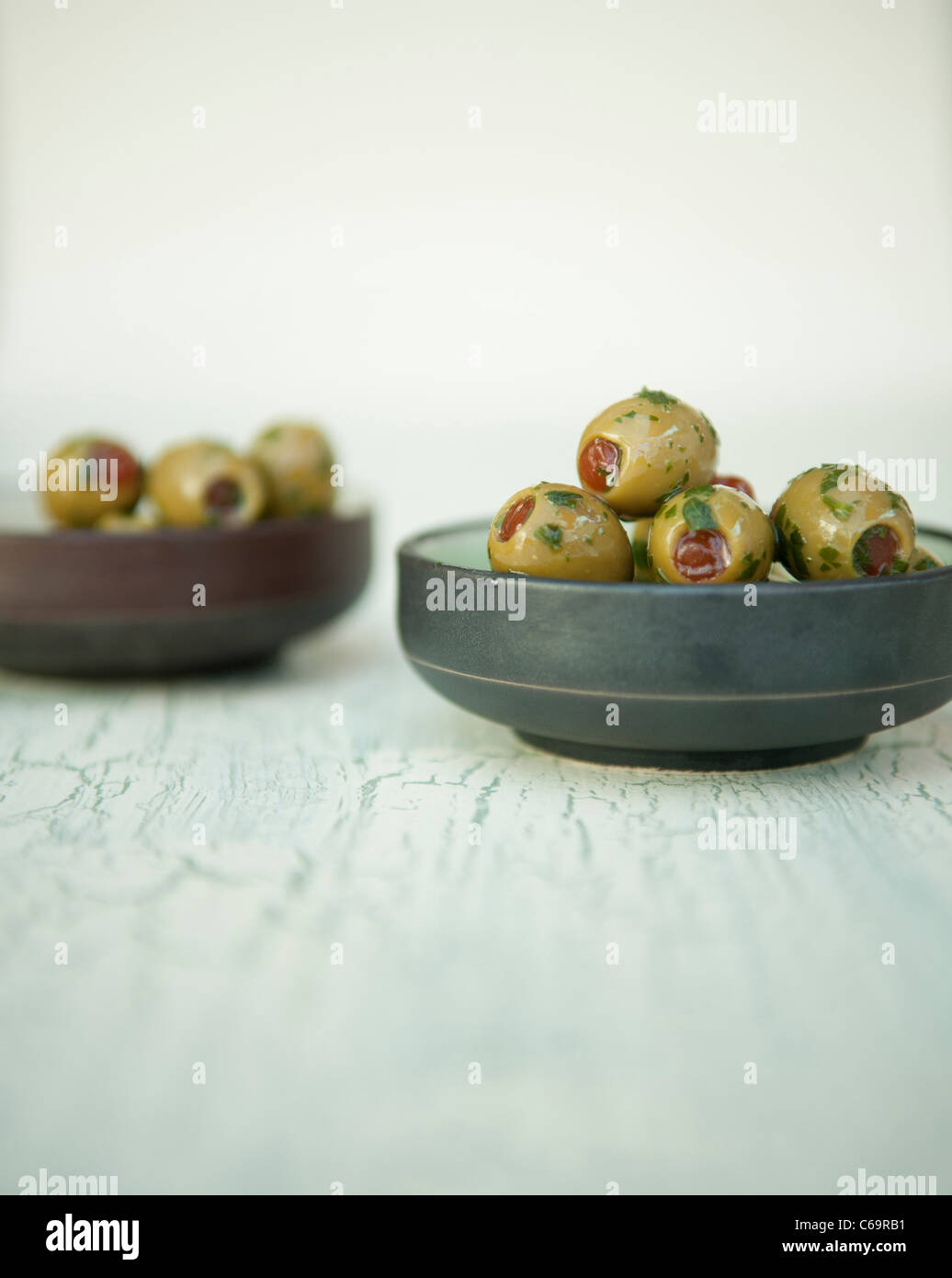 Aceitunas verdes rellenas con pimientos rojos con aceite de oliva y las hierbas en una olla Foto de stock