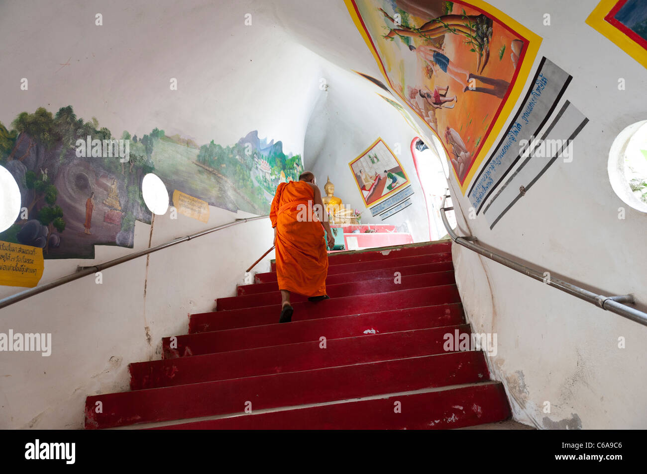 Un monje budista sube por la escalera interior del templo del dragón de Tailandia Kanchanaburi Foto de stock