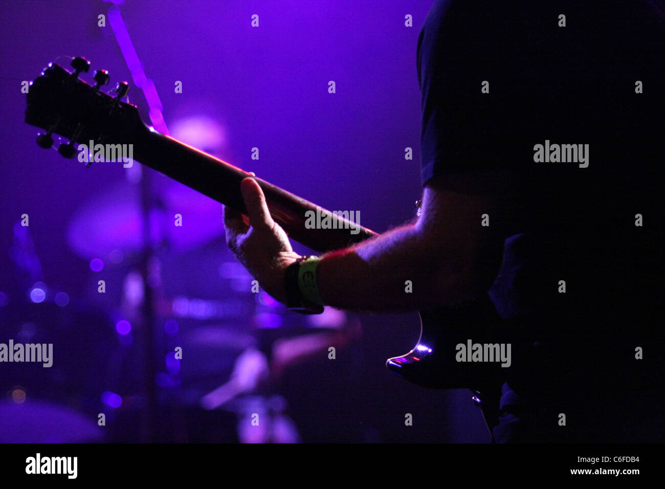 Una vista trasera de parte de un guitarrista con el baterista borrosa en el fondo Foto de stock