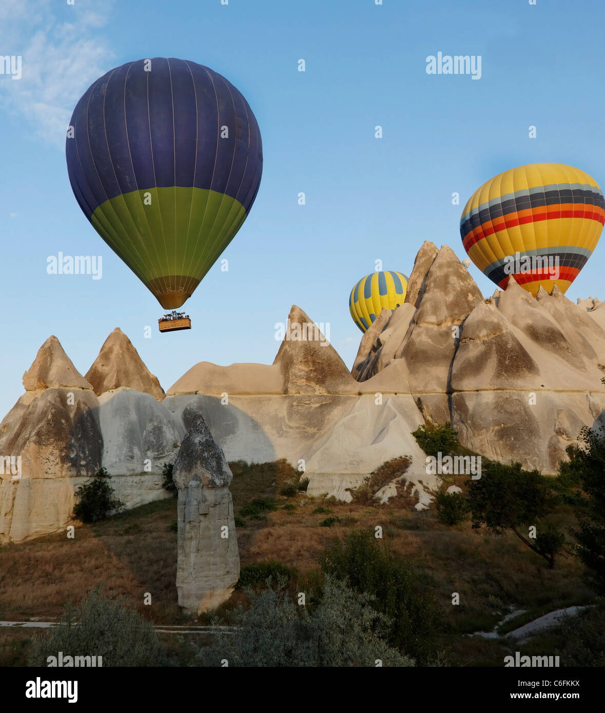 Tres globos aerostáticos multicolores en vuelo de bajo nivel a través de Capadocia picos de piedra caliza del terreno, chimeneas de las hadas, el desierto, Foto de stock