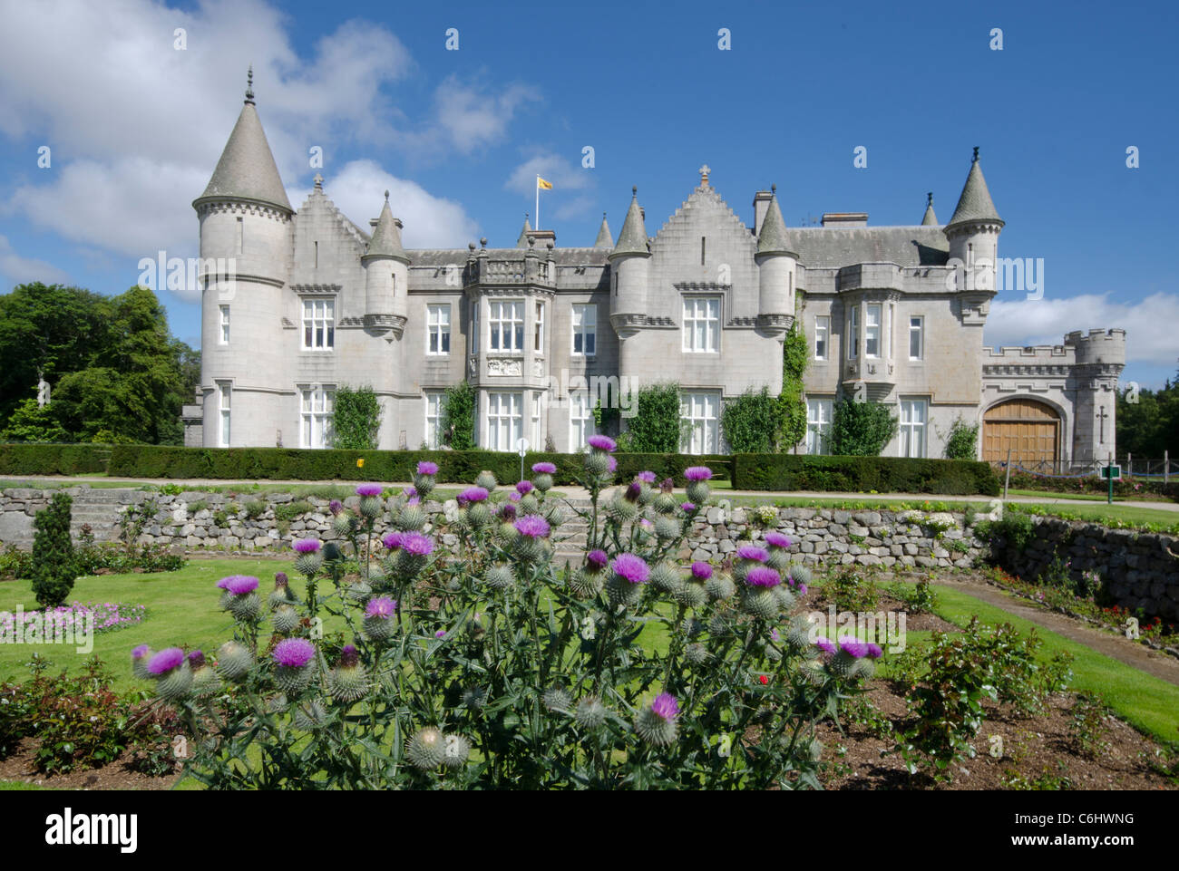 El castillo de Balmoral Royal Deeside - Queen's residencia vista del castillo desde los jardines formales con Scottish thistle en primer plano Foto de stock