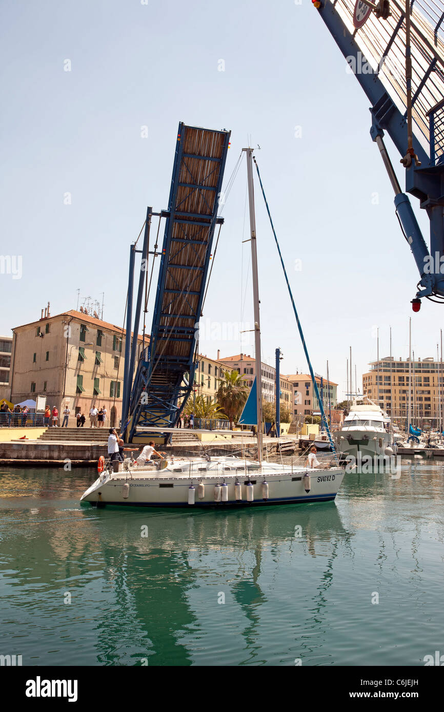 Velero en Savona, Italia marina harbour velas bajo un puente levadizo. Vista vertical. Foto de stock