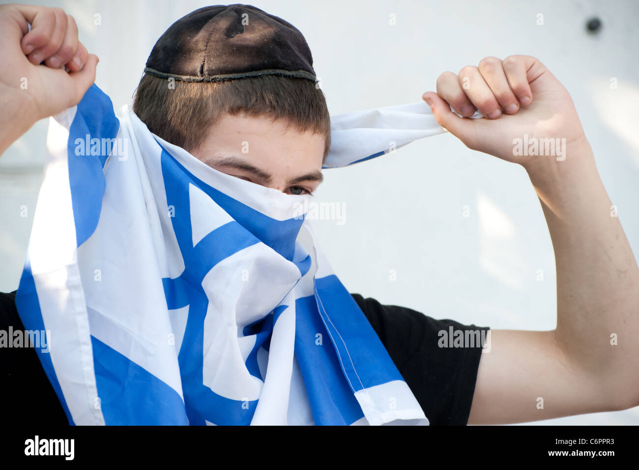 Un colono judío de jóvenes viviendo en una casa palestina en Jerusalén oriental, cubre su cara con una bandera israelí. Foto de stock