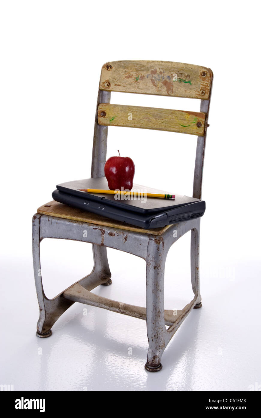 Old Fashioned silla escolar celebración de un ordenador portátil con una  manzana roja y lápiz contra un fondo blanco con reflexión Fotografía de  stock - Alamy