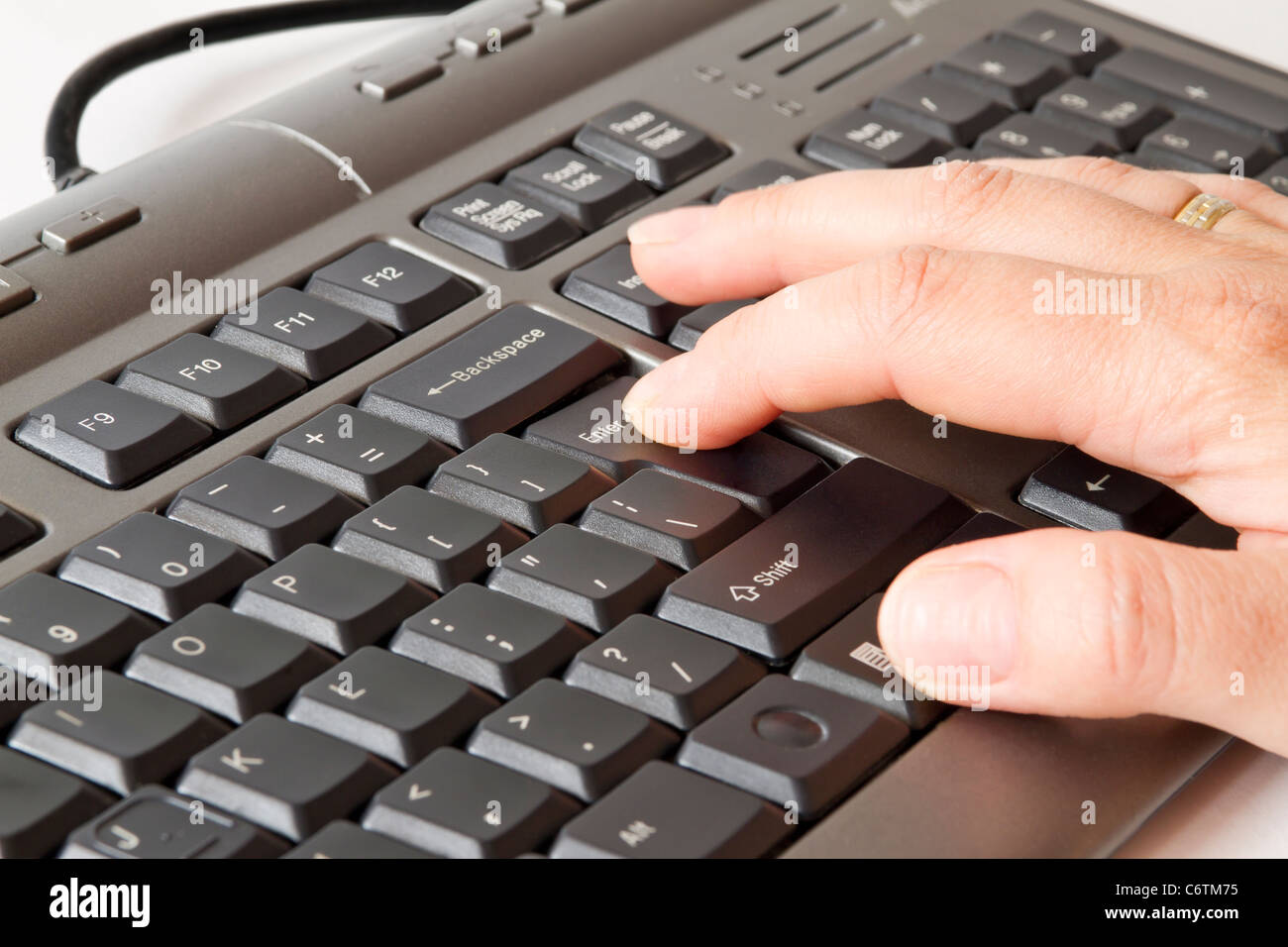 Mano pulsando la tecla Intro en el teclado Foto de stock