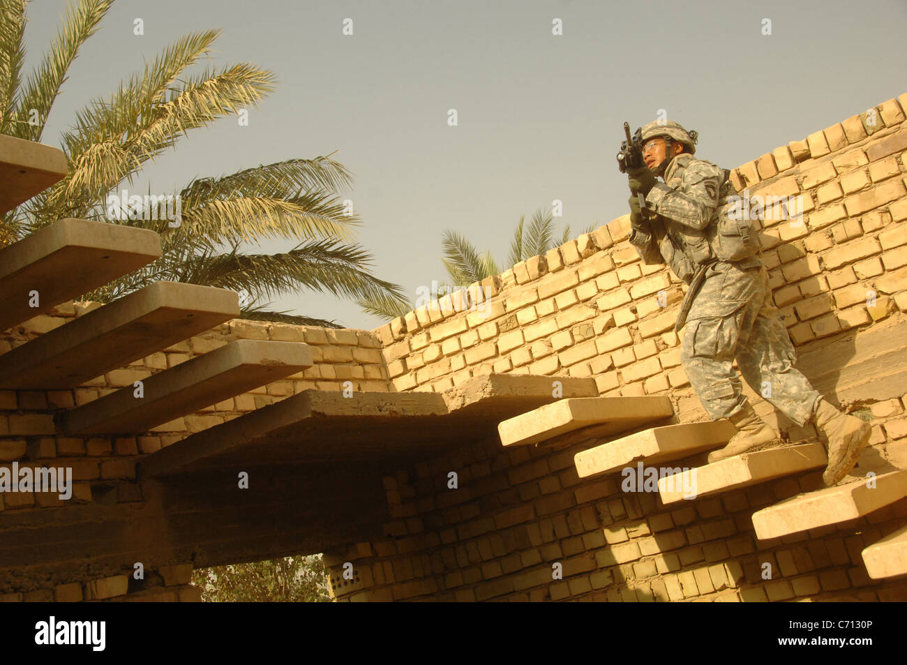 El Sargento del Ejército de Estados Unidos. Duong Tran se mueve a un tejado para proporcionar seguridad a otros soldados que busque el techo de una casa sospechosa de depósitos ocultos de armas durante una búsqueda y cordón patrulla en la ciudad de Al Mahmudiyah, Al Mahmudiyah, distrito de la provincia de Bagdad, Irak, el 4 de septiembre de 2008. Tran es asignado al 3º Batallón, 320º Regimiento de Artillería de campo, la Tercera Brigada del equipo de combate, la 101ª División Aerotransportada (de asalto aéreo). DoD foto por Spc. Richard Del Vecchio, el Ejército de los Estados Unidos. (Liberado) Foto de stock