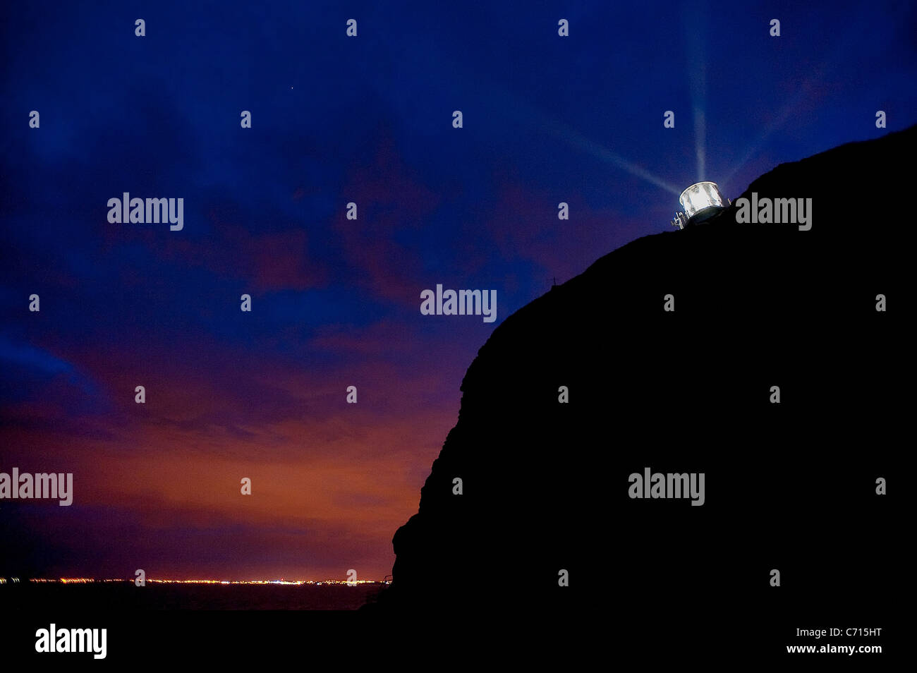 Faro de espinillas en la noche con el condado de Down costa ilumina al fondo Foto de stock