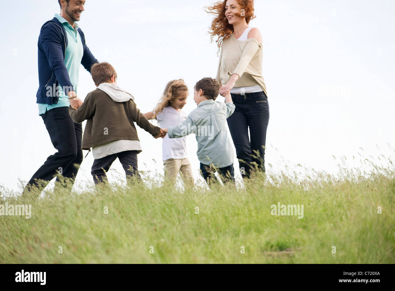 Familia jugando el anillo alrededor del color de rosa en el prado Foto de stock
