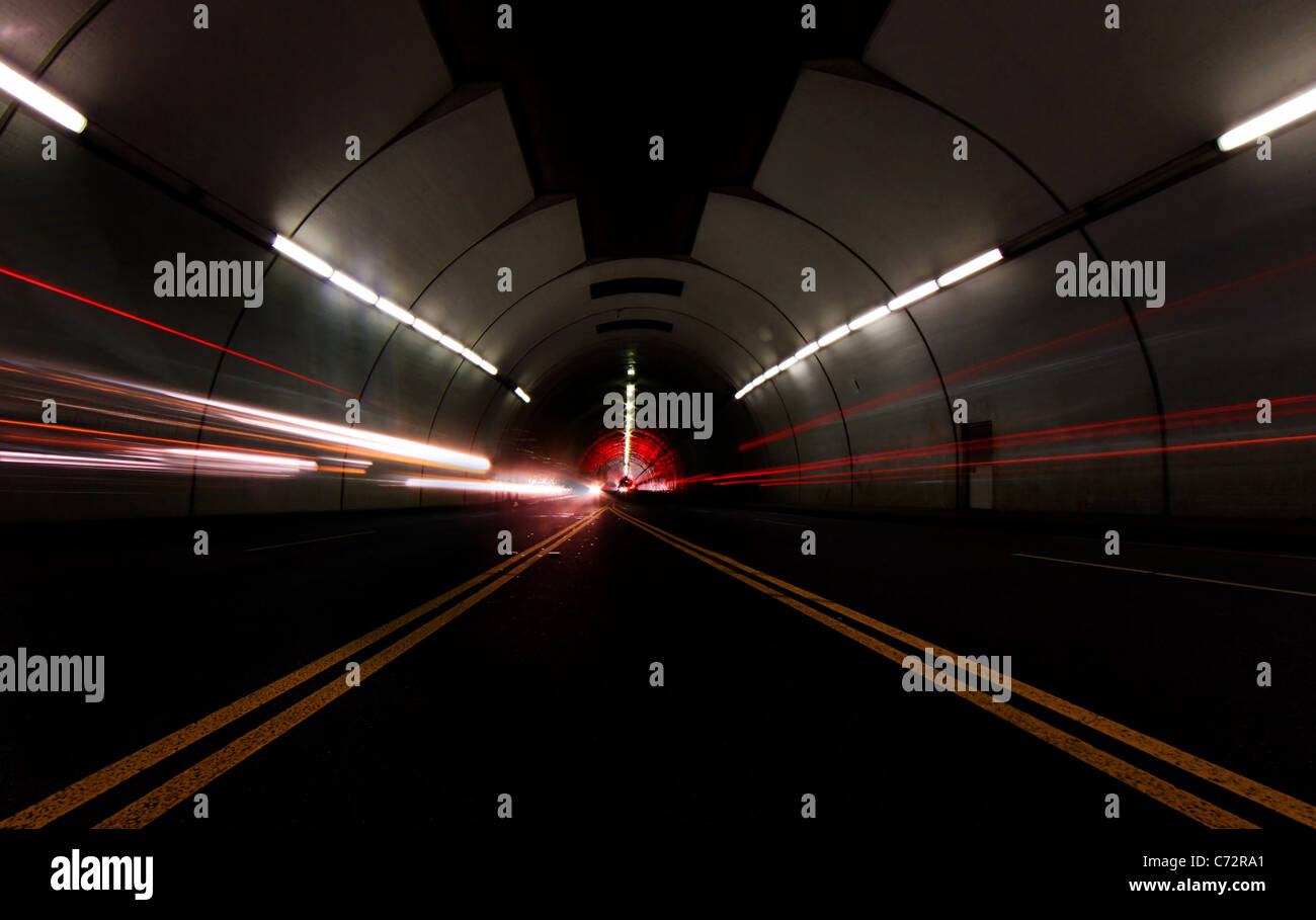 Autos pasando rápido en un túnel dejando a vetas de luz Foto de stock