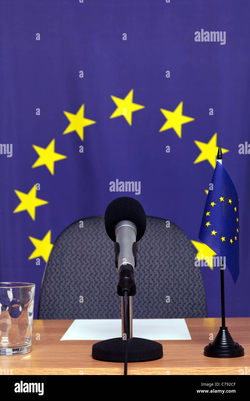 Foto de una conferencia temática europea con micrófono de escritorio y banderas. Foto de stock