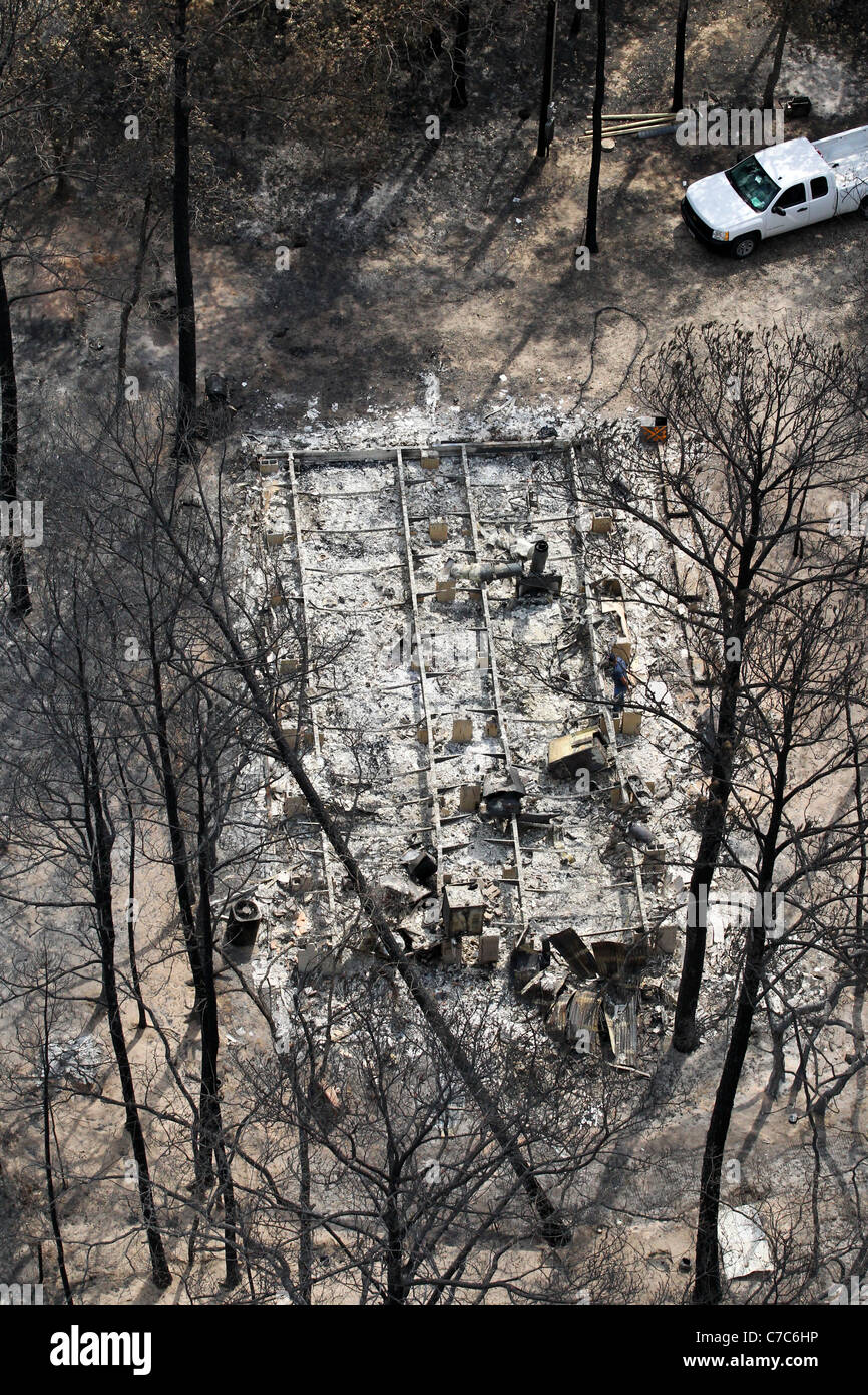 Antena de wildfire daños en Bastrop County, TX muestra la fundación de quemados casa en zona residencial de tupido bosque. Foto de stock