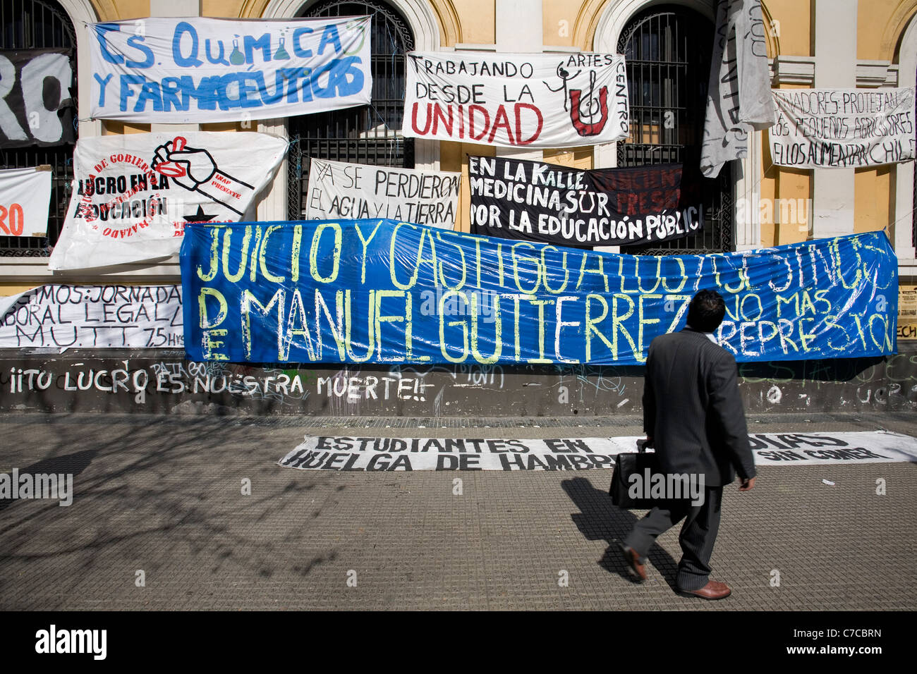 Hombre leyendo la protesta carteles colgados en la pared de la Universidad de Chile, Santiago. Foto de stock
