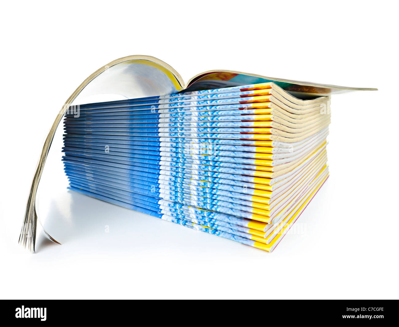 Muchas revistas apiladas en un montón con uno abierto aislado en blanco Foto de stock