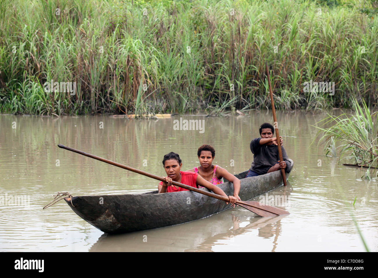 Tres niñas en una piragua en un río en Papúa Nueva Guinea Foto de stock