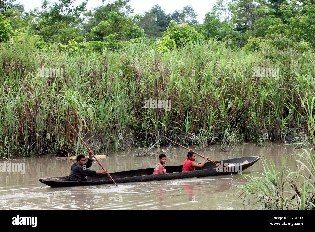 Tres niñas en una piragua en un río en Papúa Nueva Guinea Foto de stock