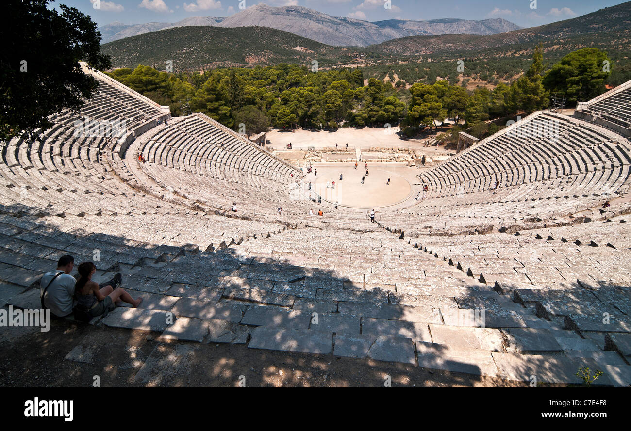Dos turistas que toman en la vista en el clásico Teatro Griego en Epidauro, antiguo Argolid, Peloponeso, Grecia. Foto de stock