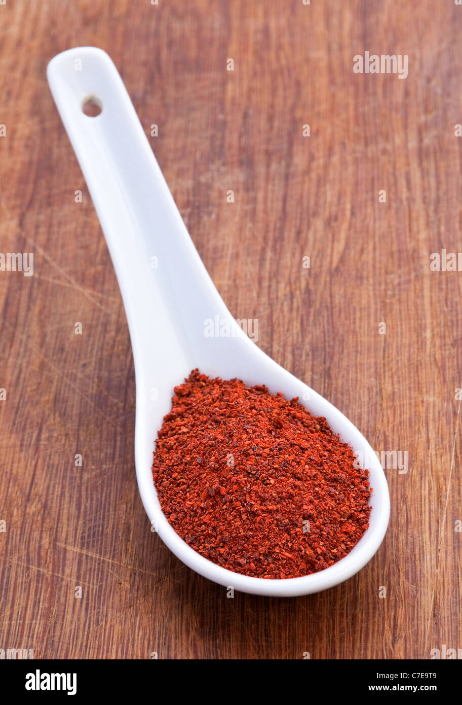 La pimienta roja en cuchara blanco sobre marrón kotchen junta Foto de stock