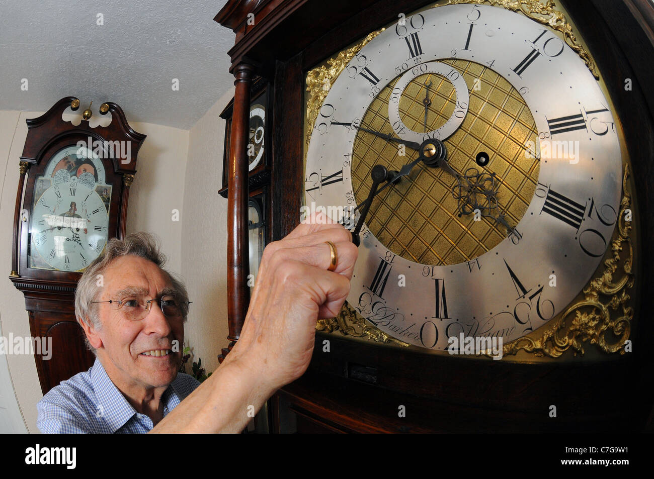 Un hombre ajustar la hora en un reloj antiguo. Foto de stock