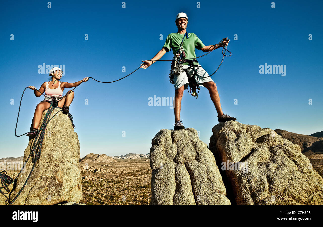 Equipo de escaladores lucha hasta la cumbre de un acantilado desafiante. Foto de stock