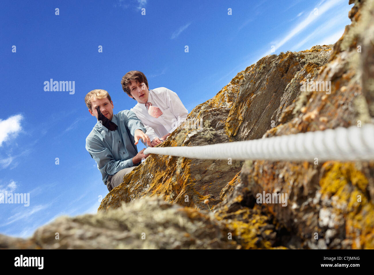 Los empresarios tirando de la cuerda sobre el acantilado Foto de stock
