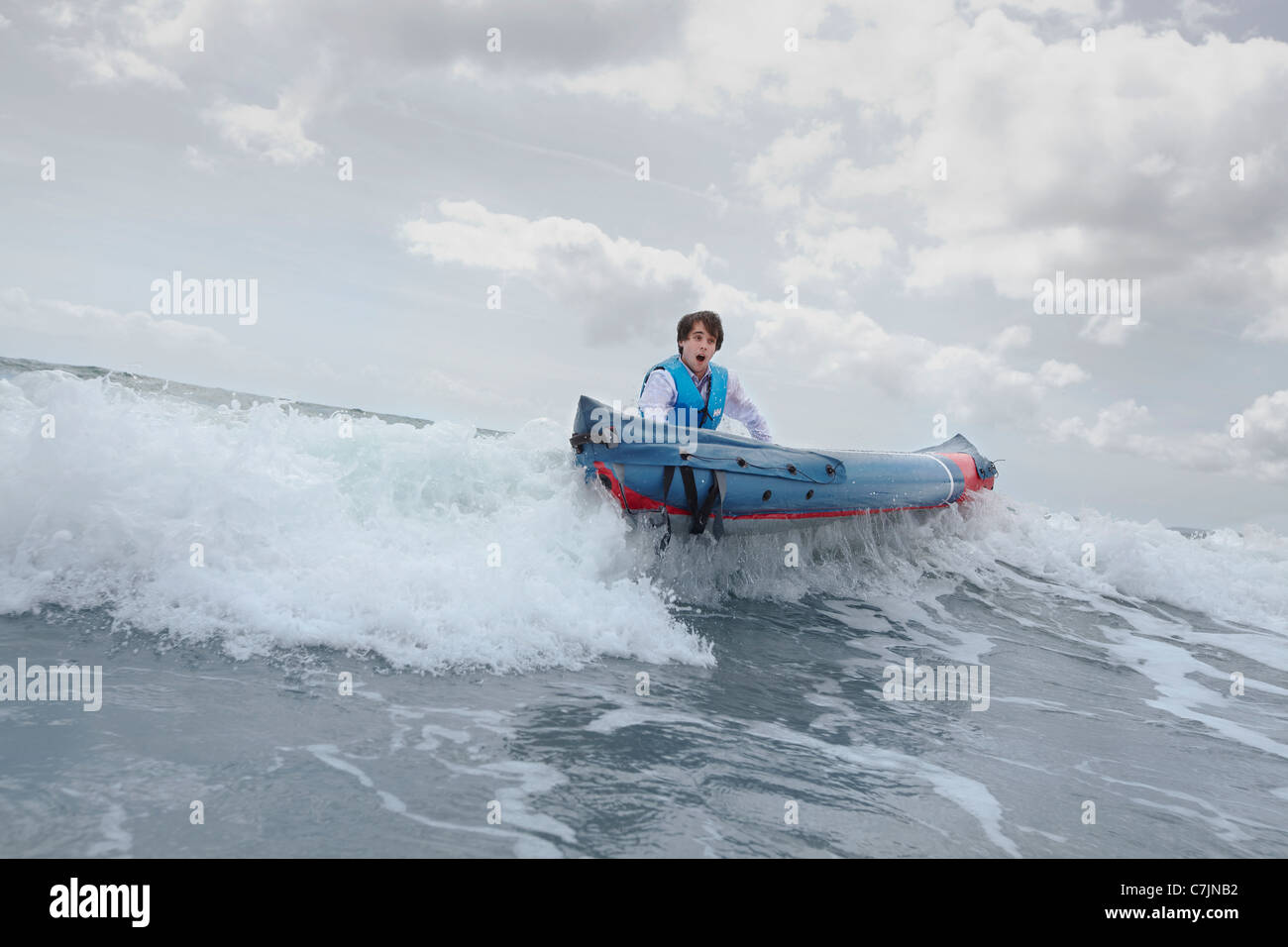 Empresario empujando una canoa en el océano Foto de stock