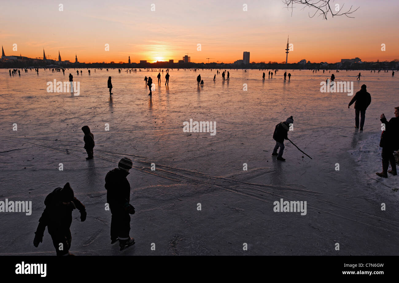 Firmemente Aussenalster, congelado Lago Alster exterior, después de la puesta del sol, la gente, la diversión, el hielo, la nieve, el invierno, Hamburgo, Alemania. Foto de stock