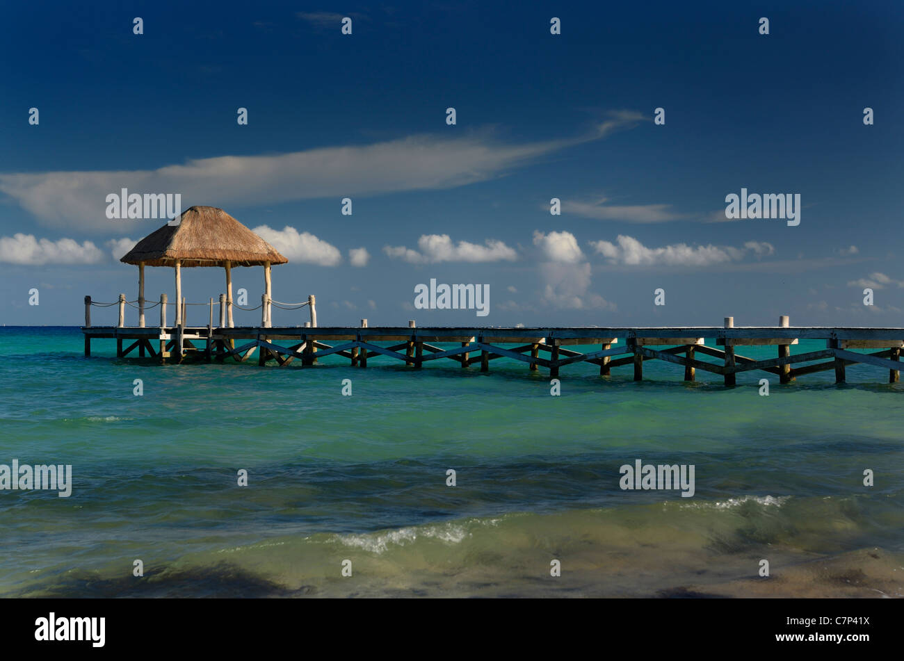 Luz del atardecer en un mirador con techo de paja en el final de un largo muelle en la costa del Golfo de México riviera maya Foto de stock