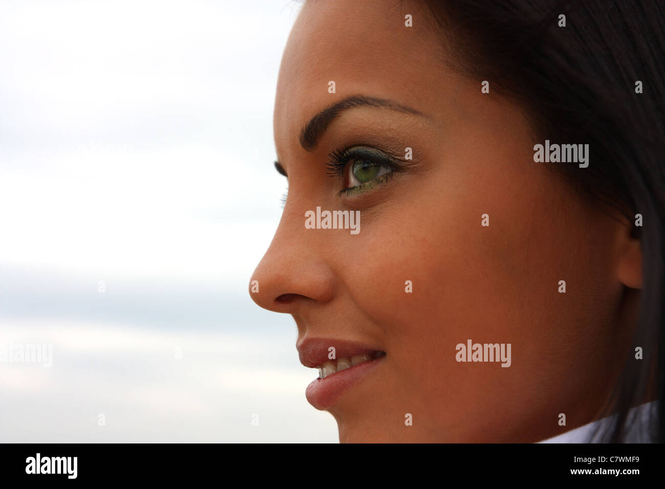 Hermoso de ojos verdes, bronceada chica cerca de perfil contra el cielo Foto de stock
