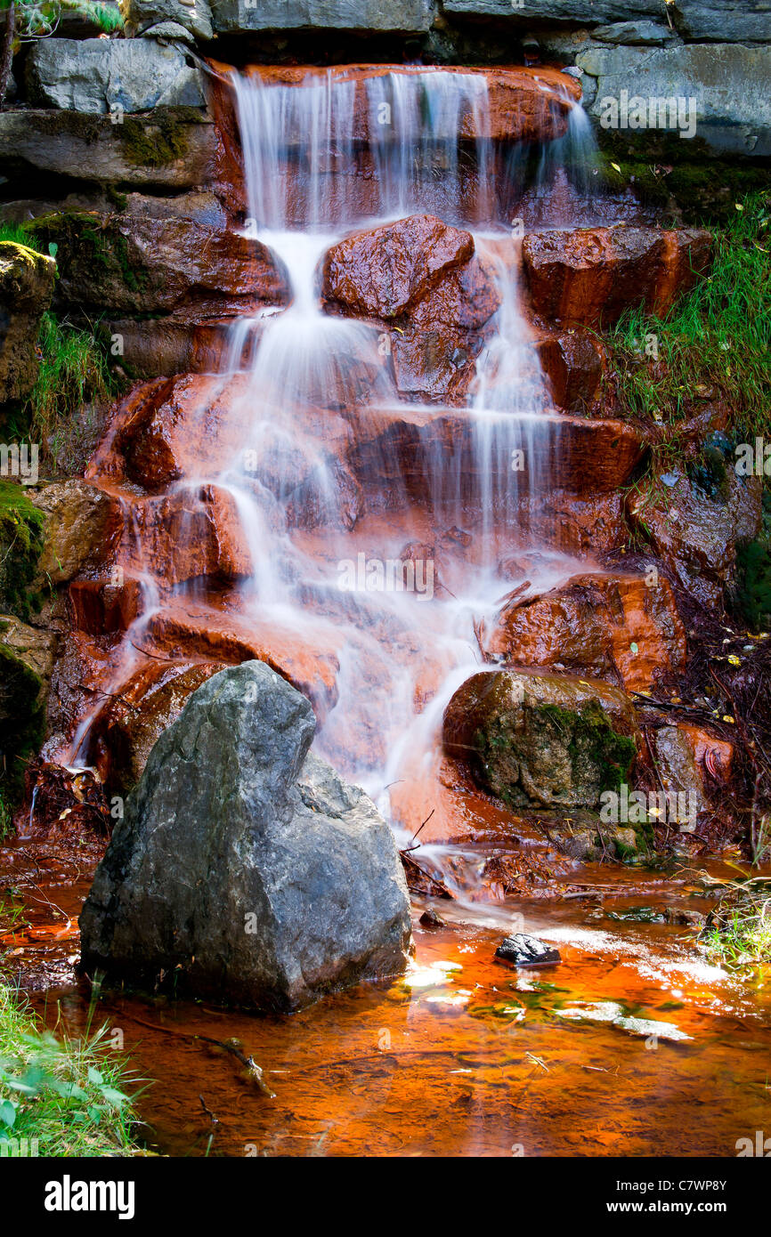 La cascada de aguas de una hermosa cascada fluyendo hacia abajo a través de las algas rojas cubiertas de piedras en Andrew Haydon Park en Ottawa, Ontario C Foto de stock