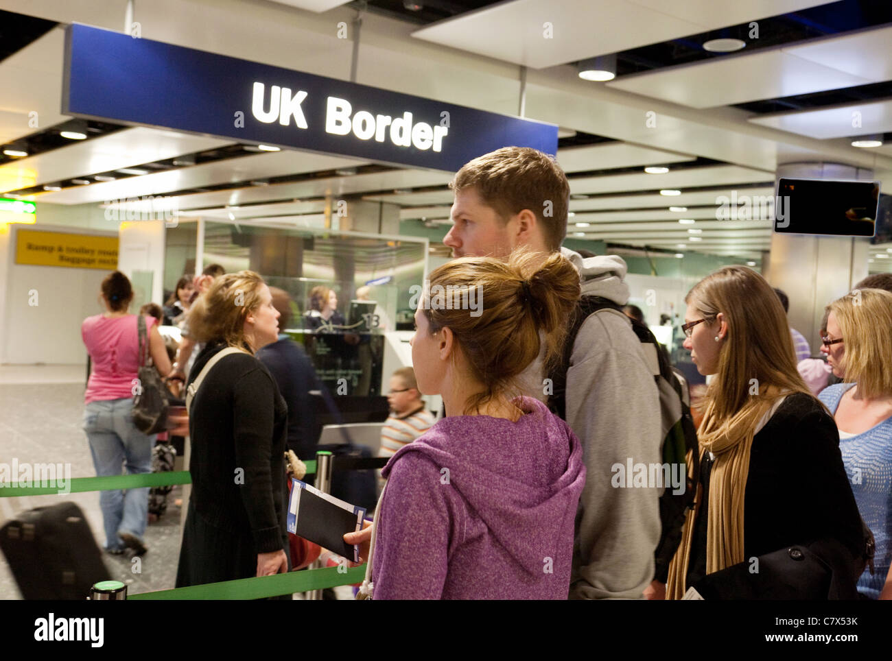 Jóvenes esperando en una cola para entrar en la frontera del Reino Unido en el control de pasaportes de inmigración, Terminal 3, aeropuerto de Heathrow, Londres Inglaterra Foto de stock