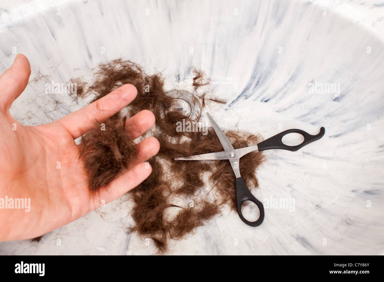 Mano sujetando el cabello después de un corte de pelo auto Foto de stock