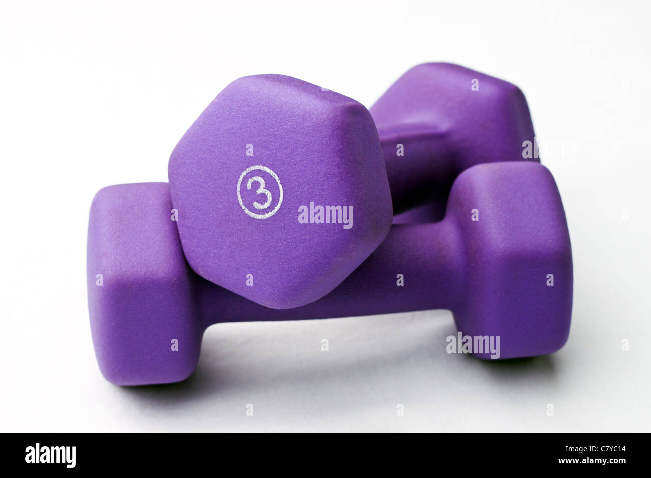 Un par de 3 lb púrpura pesas de neopreno apilados contra un fondo blanco. Foto de stock