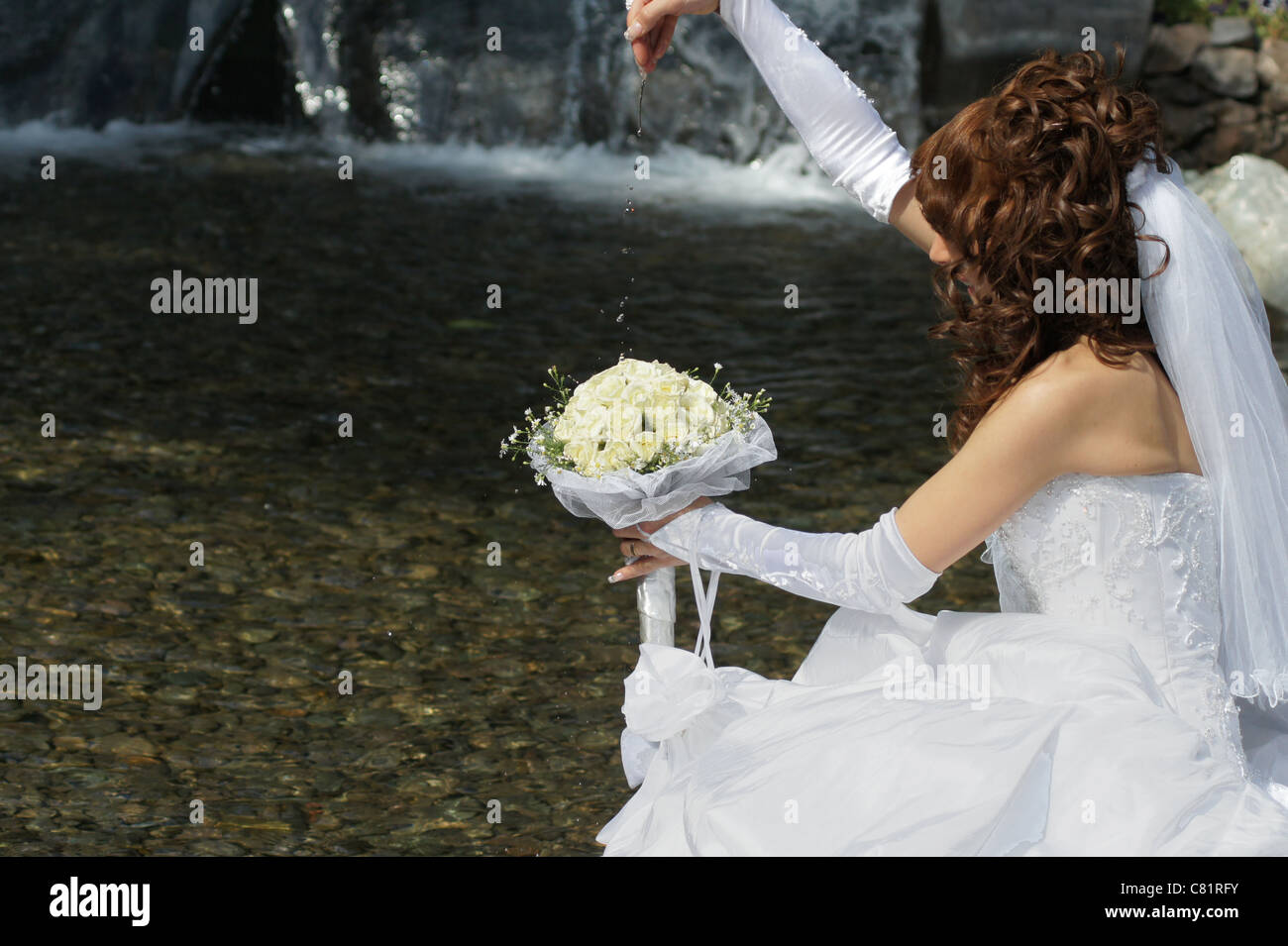 Novia boda jugando y admirando con las gotitas de agua Fotografía de stock  - Alamy