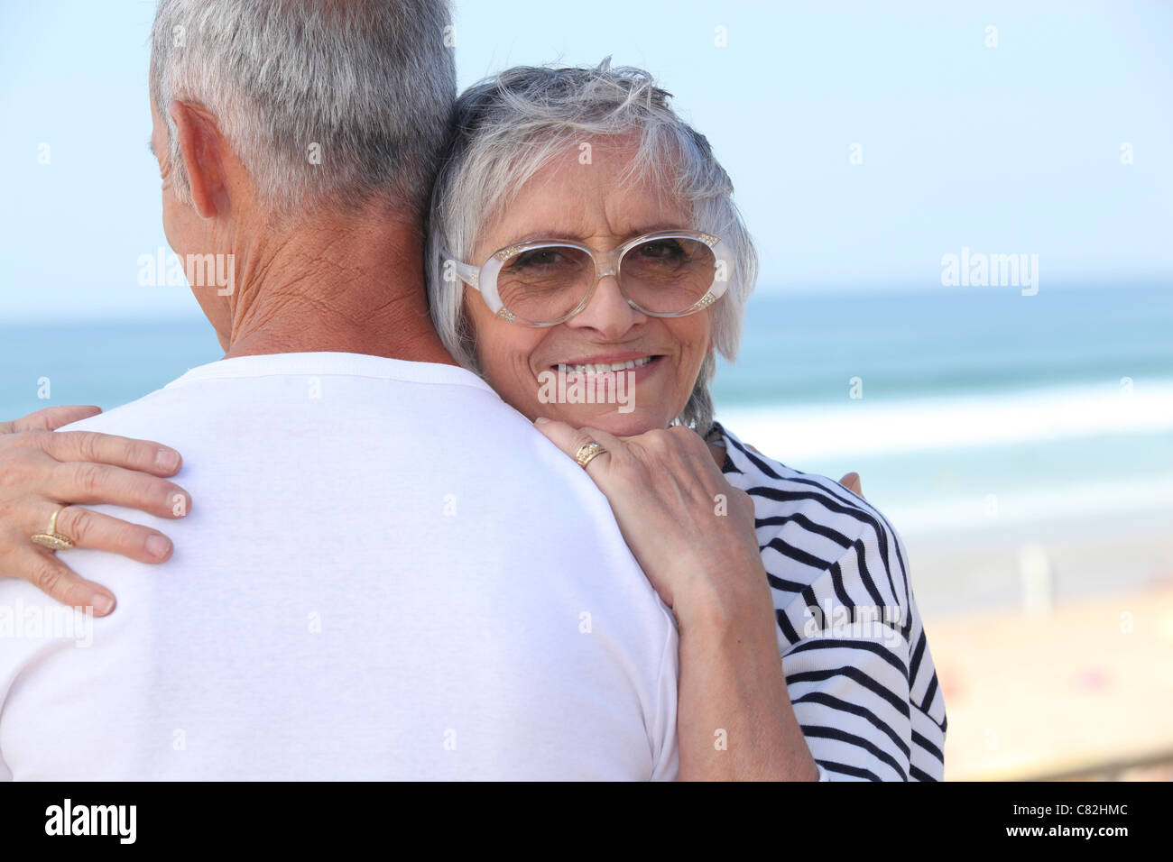 Pareja de ancianos abrazarse por una playa Foto de stock
